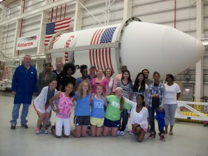 SSEP Mission 5 launch delegation posing in from of the Antares rocket that successfully carried the selected experiment ‘Oxidation in Space” to the International Space Station in July 2014. (aSTEAM Village)