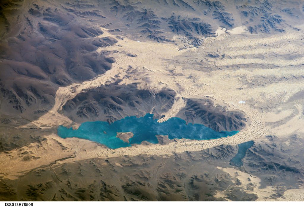 Har (or Black) Lake is located in the western part of Mongolia within the Valley of Lakes--part of a system of closed basins that stretches across central Asia. This oblique view captures the dynamic nature of the landscape of Har Lake. The lake is encircled by sand dune fields which encroach on the lower slopes of the Tobhata Mountains to the west and south. This image was captured on Sept. 15, 2006. 