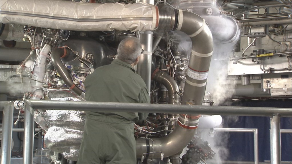 A worker inspects the machinery of an RS-25 engine