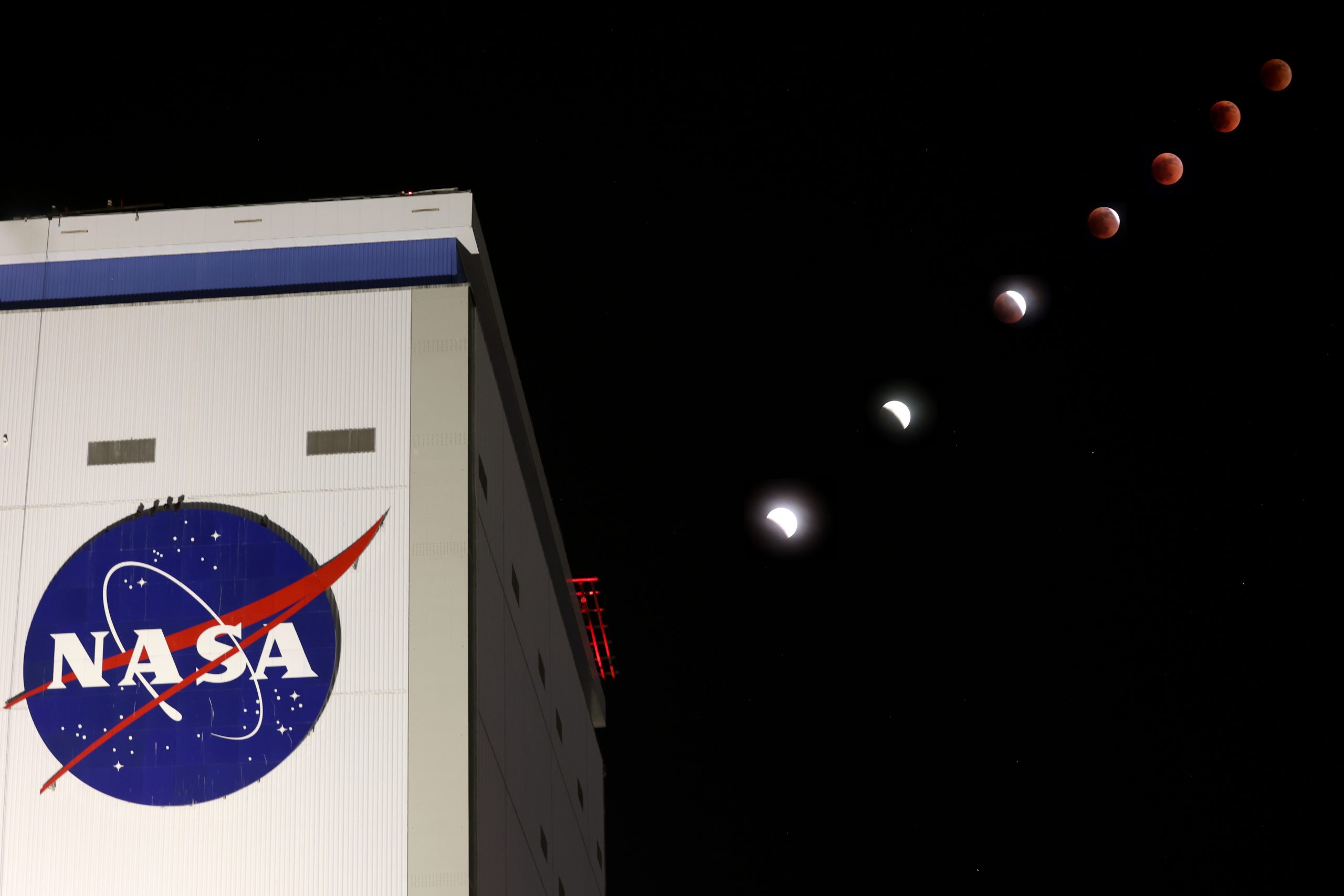 Una toma de 7 fases de un eclipse lunar con un edificio con el logotipo de la NASA en primer plano.