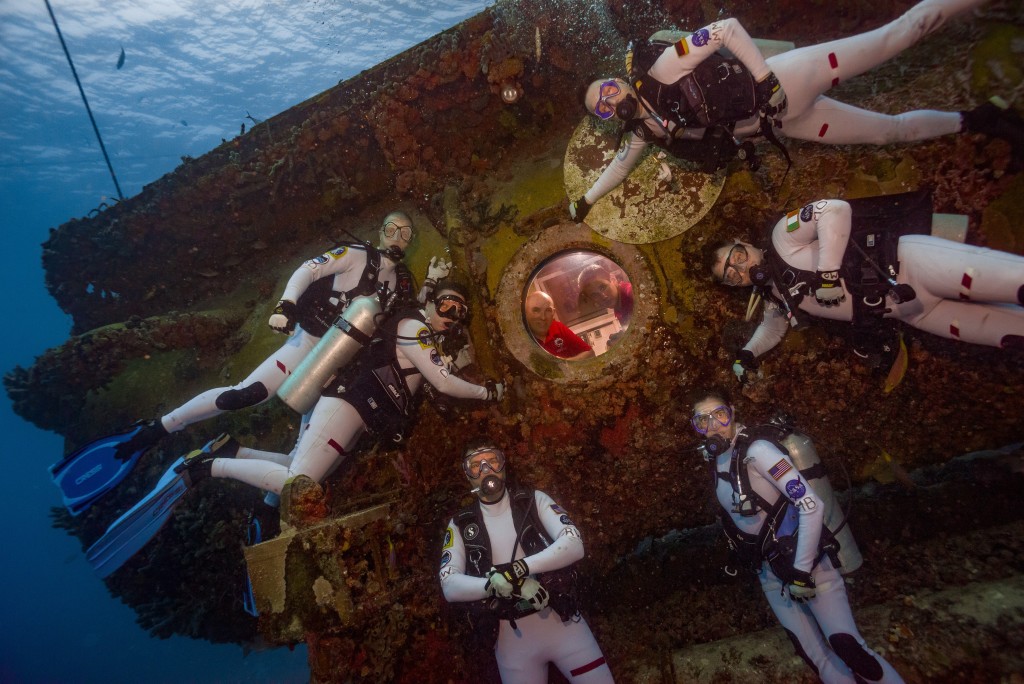 Pictured at the end of Mission Day 1 are the NEEMO 21 aquanauts, clockwise from top: Matthias Maurer (ESA), Marc O Griofa (Teloregen/VEGA/AirDocs), NASA astronaut Megan McArthur, NASA astronaut Reid Wiseman, Dawn Kernagis (Institute for Human & Machine Cognition), and Noel Du Toit (Naval Postgraduate School). Inside the Aquarius habitat are Florida International University Habitat Technicians Hank Stark (left) and Sean Moore (right).