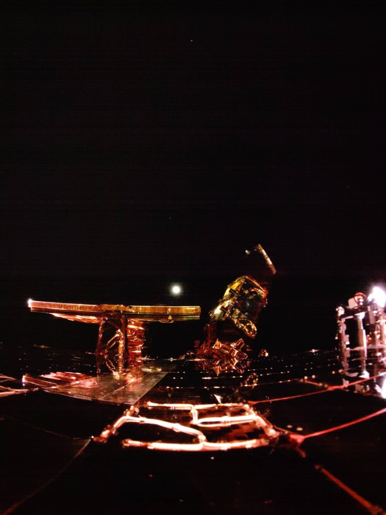 An image from the top deck of Firefly's Blue Ghost lunar lander in the darkness of space with the lit Moon in the distance. 