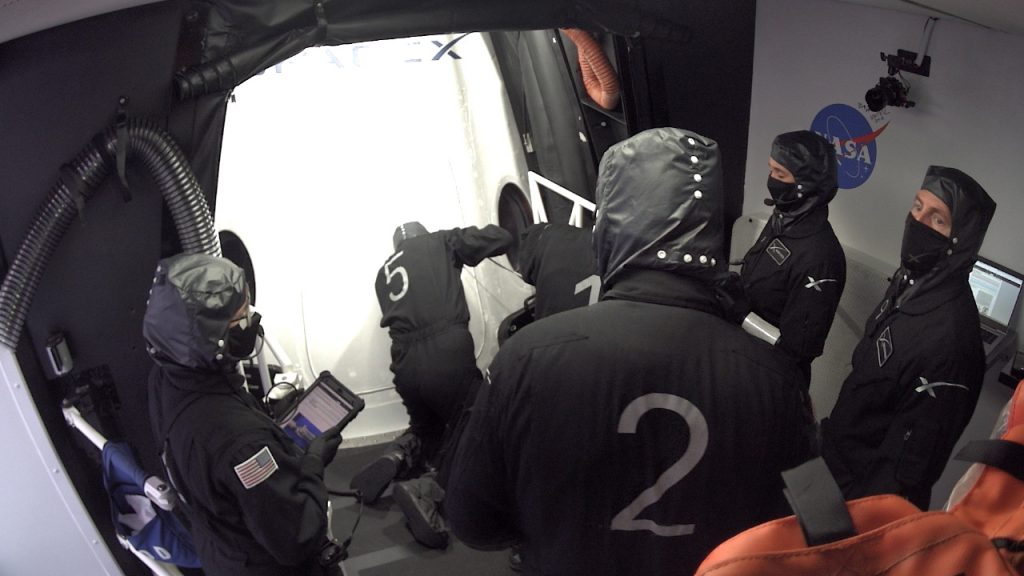 SpaceX technicians in the White Room at Launch Complex 39A close the Crew Dragon's side hatch and check for leaks. 