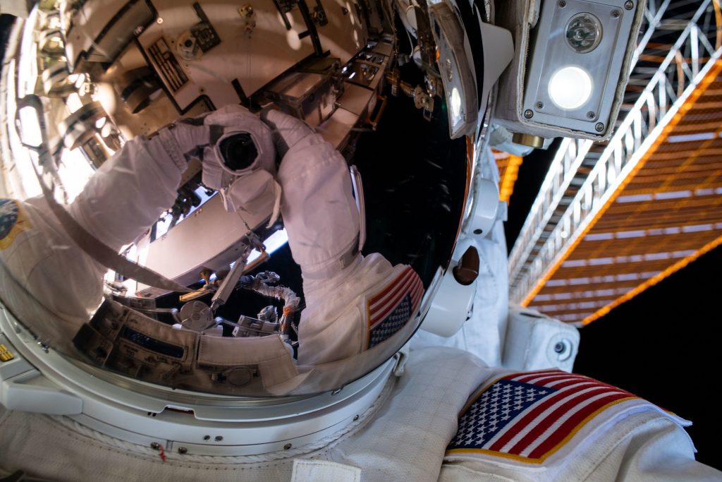 NASA astronaut Bob Behnken’s spacesuit gloves and camera are reflected in his helmet’s visor in this “space-selfie” taken during a spacewalk on June 26, 2020.