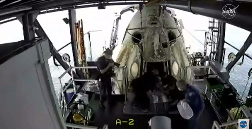 Recovery personnel offer assistance as NASA astronaut Behnken exits the SpaceX Crew Dragon spacecraft.