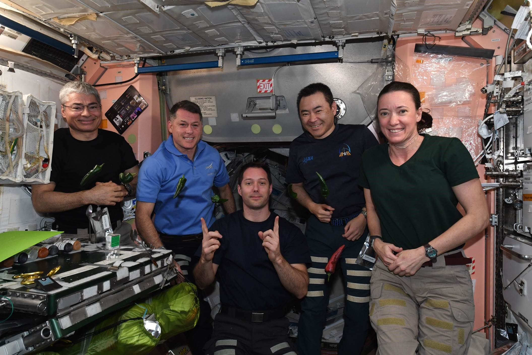 Expedition 66 crew members are photographed with chile peppers aboard the International Space Station.