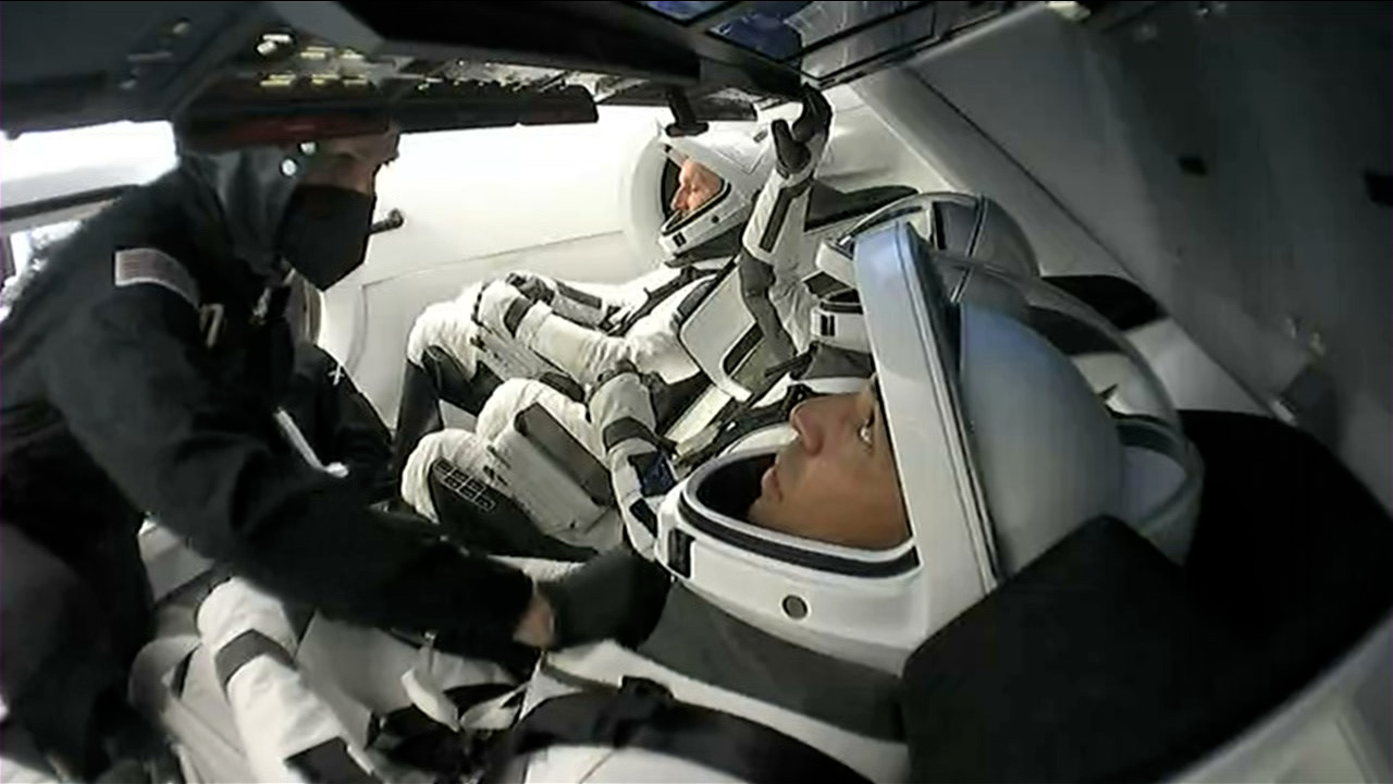 Technicians help secure NASA's SpaceX Crew-3 astronauts in their seats just after entering the Crew Dragon spacecraft.