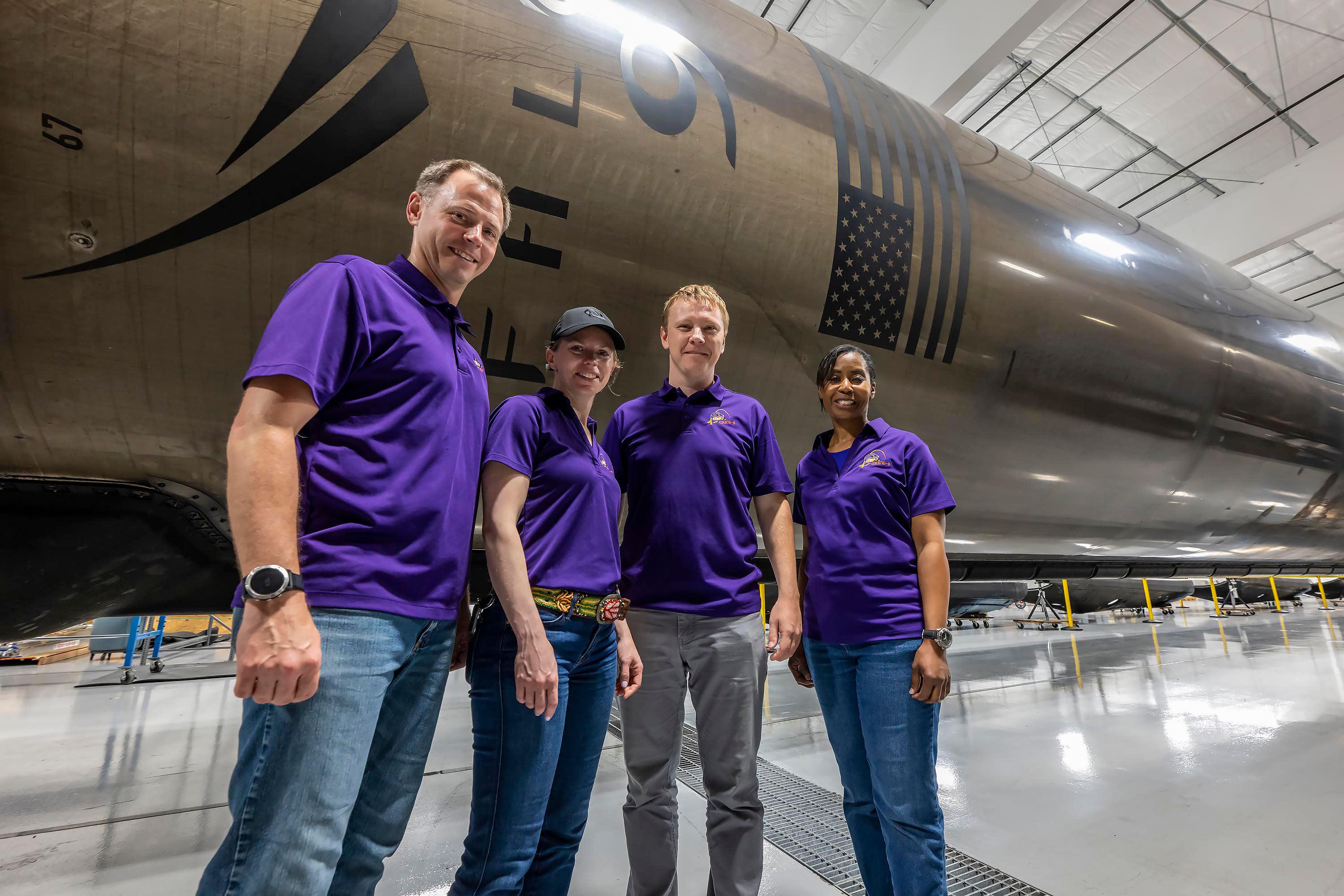 NASA’s SpaceX Crew-9 stands in front of a Falcon 9 first-stage booster at SpaceX’s HangarX facility in Florida. 