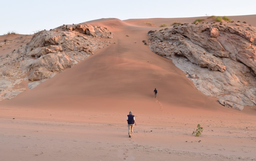 Brent Holben and his son, Sam, hiking toward the top of a dune to catch the sunset. Credit: NASA/Jane Peterson