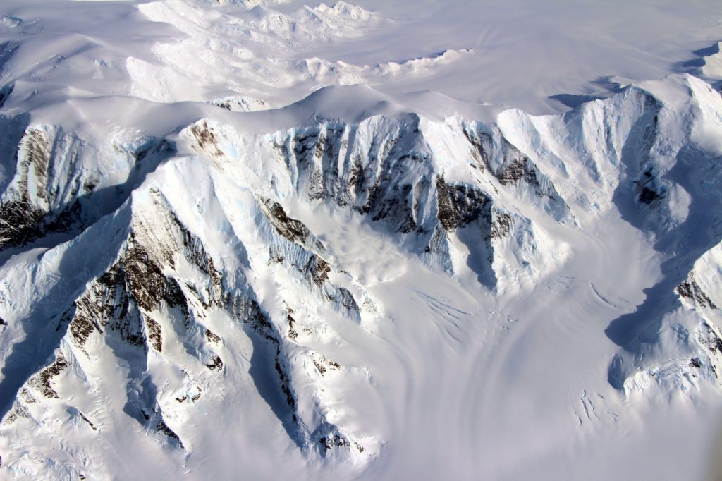 The Mountains of Alexander Island as seen from the NASA DC-8 on October 15, 2016.  The curious feature near the floor of the valley at center may be a small patch of fog, or it may be an avalanche in progress. Credit: NASA/John Sonntag