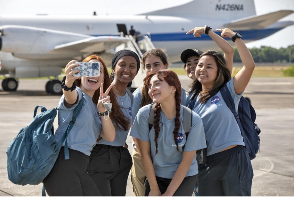 Six students pose in front of the P-3 aircraft.