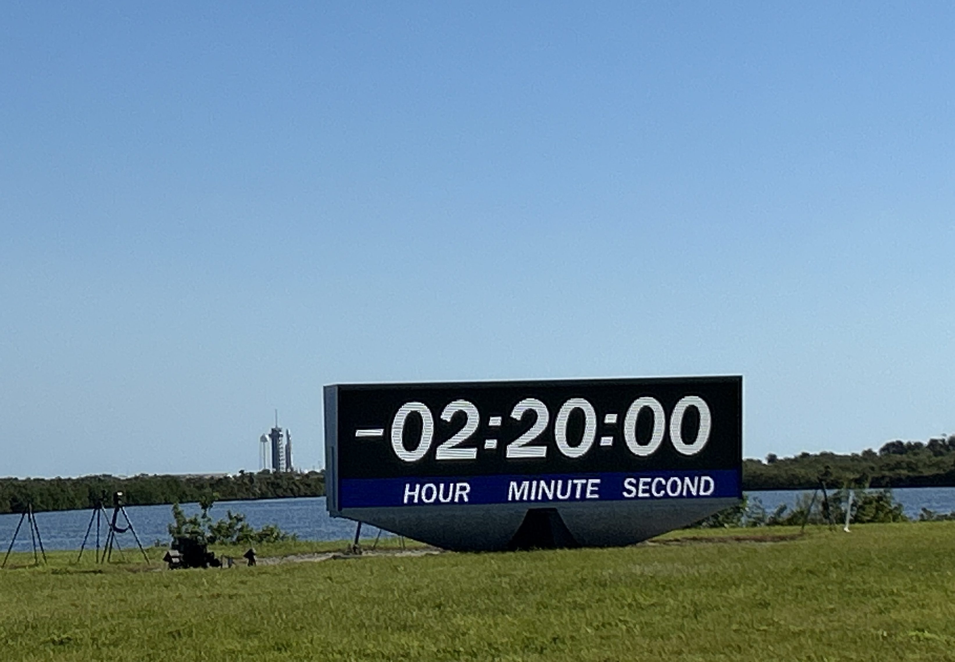 NASA's Europa Clipper mission is poised to launch atop a SpaceX Falcon Heavy rocket in the distance behind the iconic countdown clock at the NASA News Center at Kennedy Space Center in Florida. 