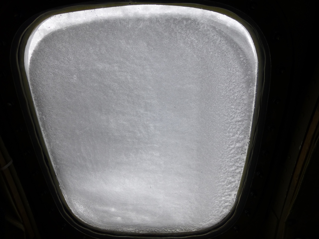 Windblown snow covers one of the P-3's side windows