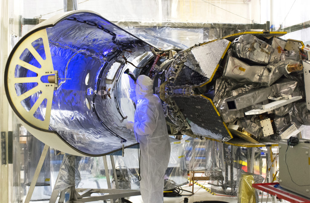 A technician uses an ultraviolet light to inspect the Orbital ATK Pegasus XL payload fairing 