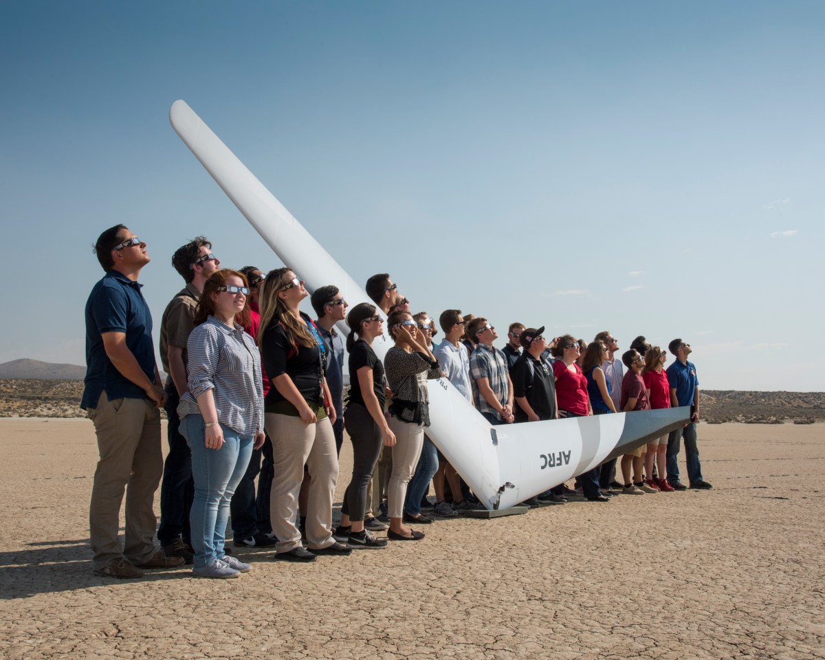 NASA Armstrong interns wearing eclipse glasses and standing with the PRANDTL glider