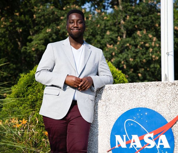 Albert Kodua, a former NASA intern at the Goddard Space Flight Center in Maryland, standing next to a NASA sign.