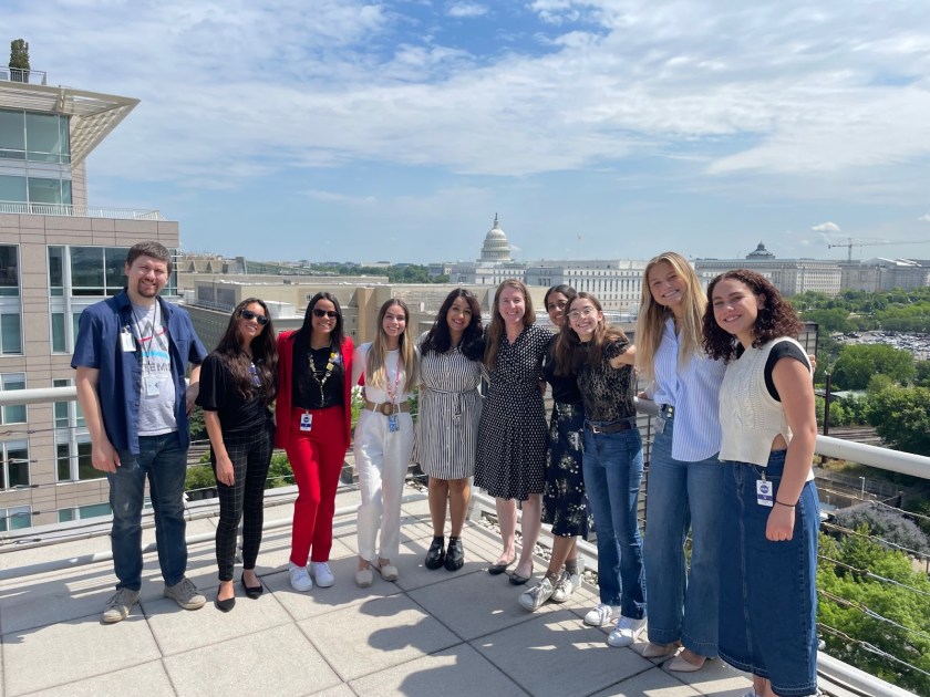 Alt Text: Nora Lowe poses with a group of interns and Chief Scientist and Senior Climate Advisor Katherine Calvin on the rooftop of NASA Headquarters. The Capitol building is visible in the background, providing a distinctive Washington, D.C. backdrop. Image Credit: Nora Lowe