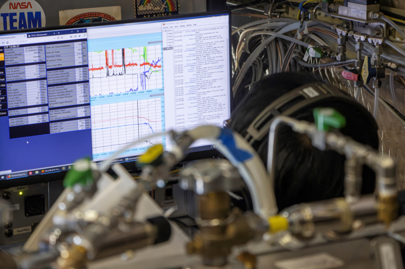 A computer screen with graphs of data moving sharply up and down is watched while aboard an aircraft.