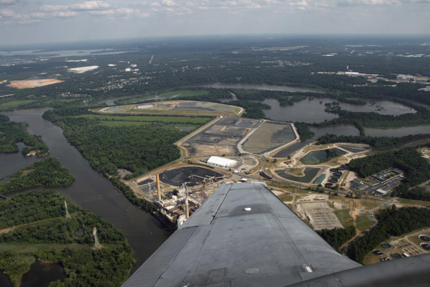 A large industrial area beside a waterway is seen from above. 