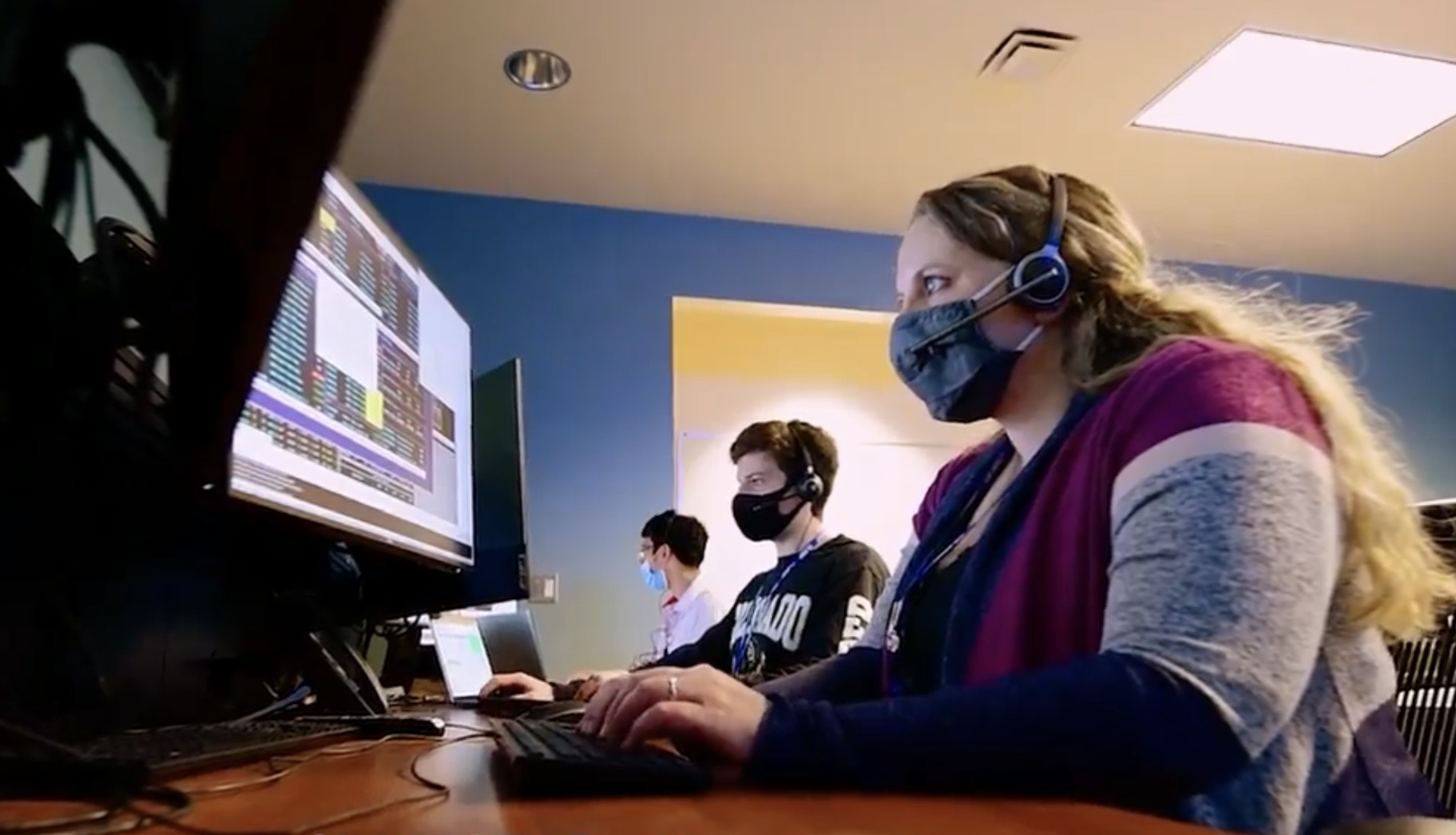 A college aded young woman sits at a computer.