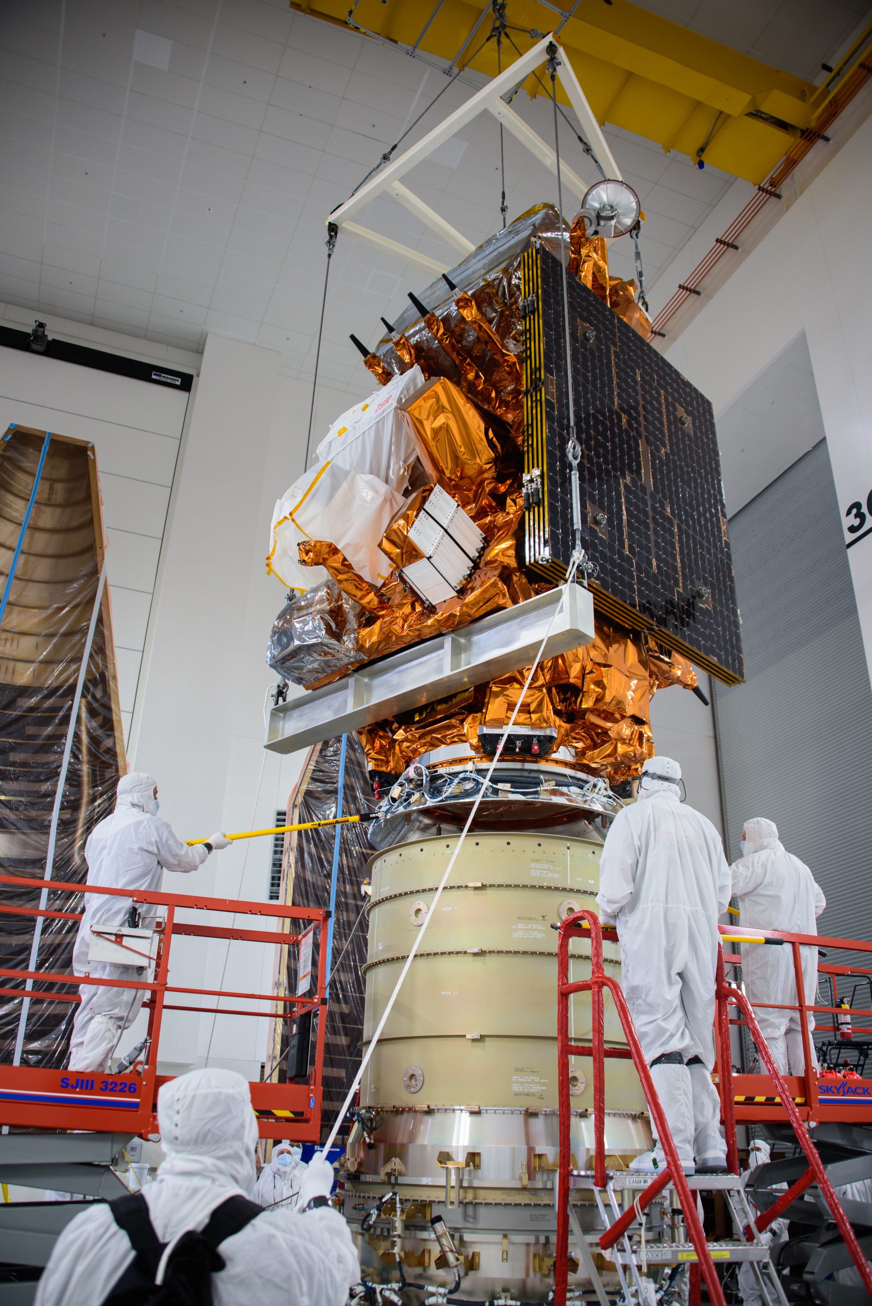 Technicians assist as a crane lowers the National Oceanic and Atmospheric Administration’s (NOAA) Joint Polar Satellite System-2 (JPSS-2) onto the Low-Earth Orbit Flight Test of an Inflatable Decelerator (LOFTID) payload inside the Astrotech Space Operations facility at Vandenberg Space Force Base (VSFB) in California on Oct. 5, 2022.