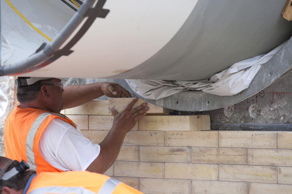 A construction worker with J.P. Donovan of Rockledge, Florida, installs new heat-resistant bricks around one of the overpressure water system pipes on the north side of the flame trench at Launch Pad 39B