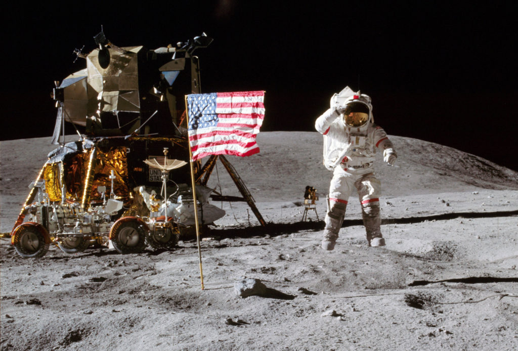 Apollo 16 commander John Young leaps from the lunar surface as he salutes the United States flag at the Descartes landing site during the mission's first moon walk. The Lunar Module is on the left and the Lunar Roving Vehicle is parked in front. Photo credit: NASA/Charlie Duke