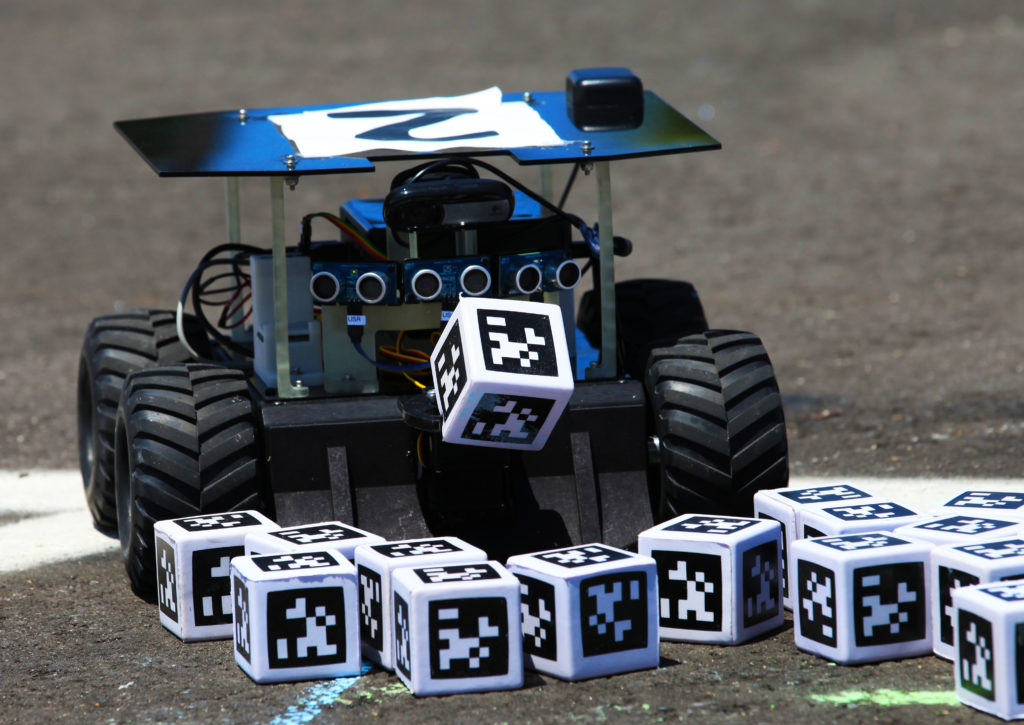 At the 2017 competition, a Swarmie robot finds a "resource" cube marked with an AprilTag. In the Swarmathon competition, students were asked to develop computer code for the small robots, programming them to look for "resources" in the form of cubes with AprilTags. Photo credit: NASA/Kim Shiflett