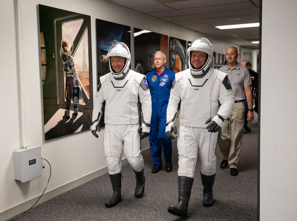 Los miembros de la tripulación de Demo-2 Robert Behnken (derecha) y Douglas Hurley caminan por el pasillo del Edificio de Operaciones y Comprobaciones Neil A. Armstrong en el Centro Espacial Kennedy en Florida durante un ensayo de vestimenta seca antes del lanzamiento de SpaceX Demo-2 de la NASA.