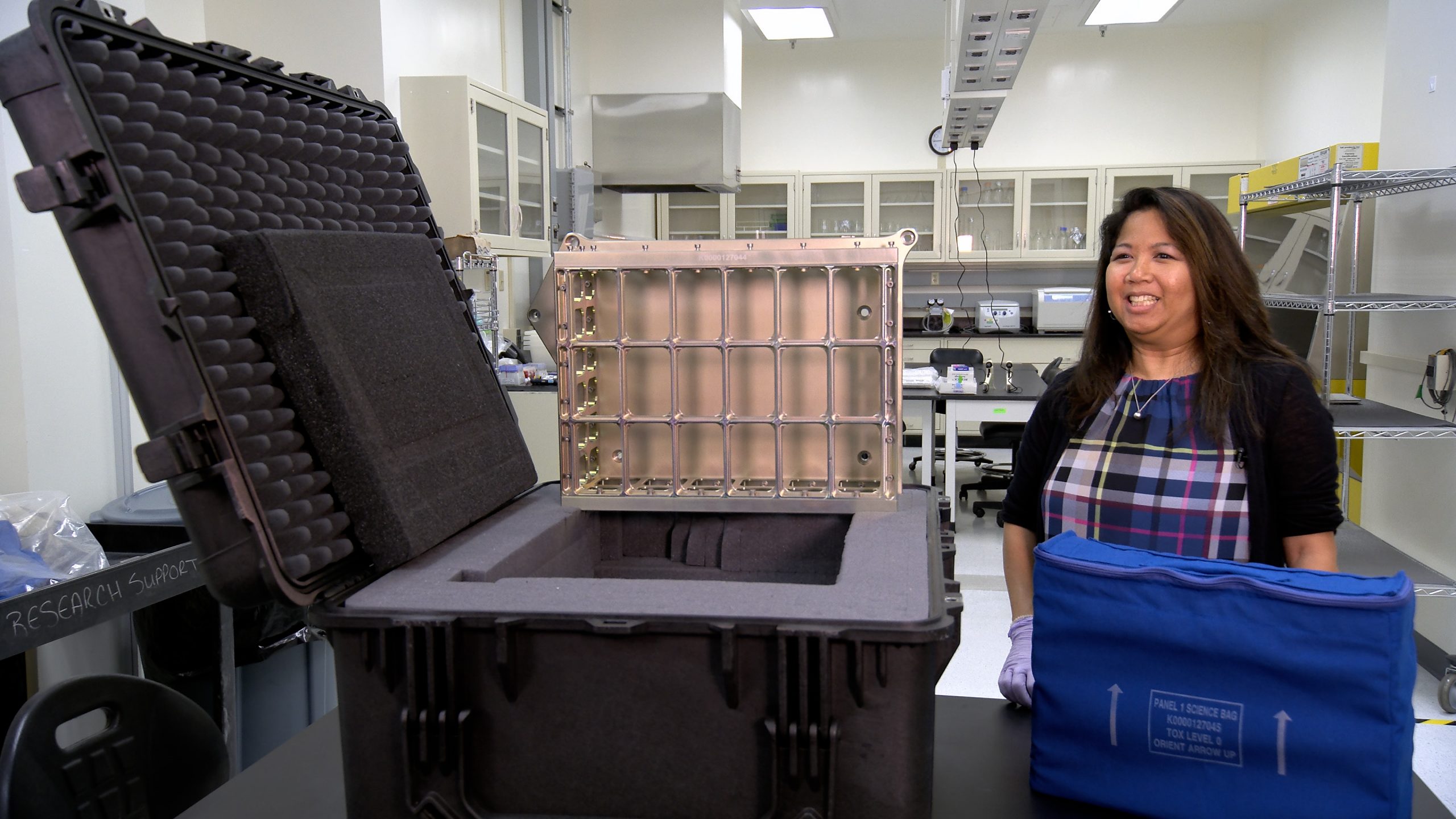 NASA Project Manager Dinah Dimapilis is photographed next to one of the container assemblies that will carry the agency's Biology Experiment-1 on the Artemis I mission.