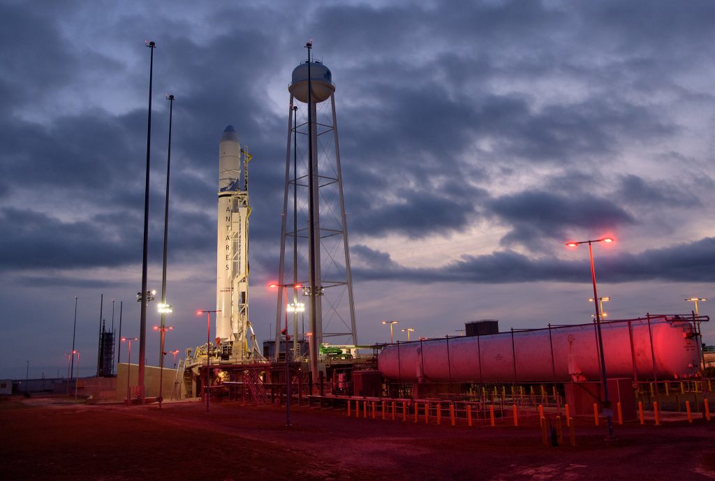 A rocket stands on a launch pad with dark blue clouds in the sky.