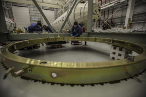 technicians with large brassy ring in foreground