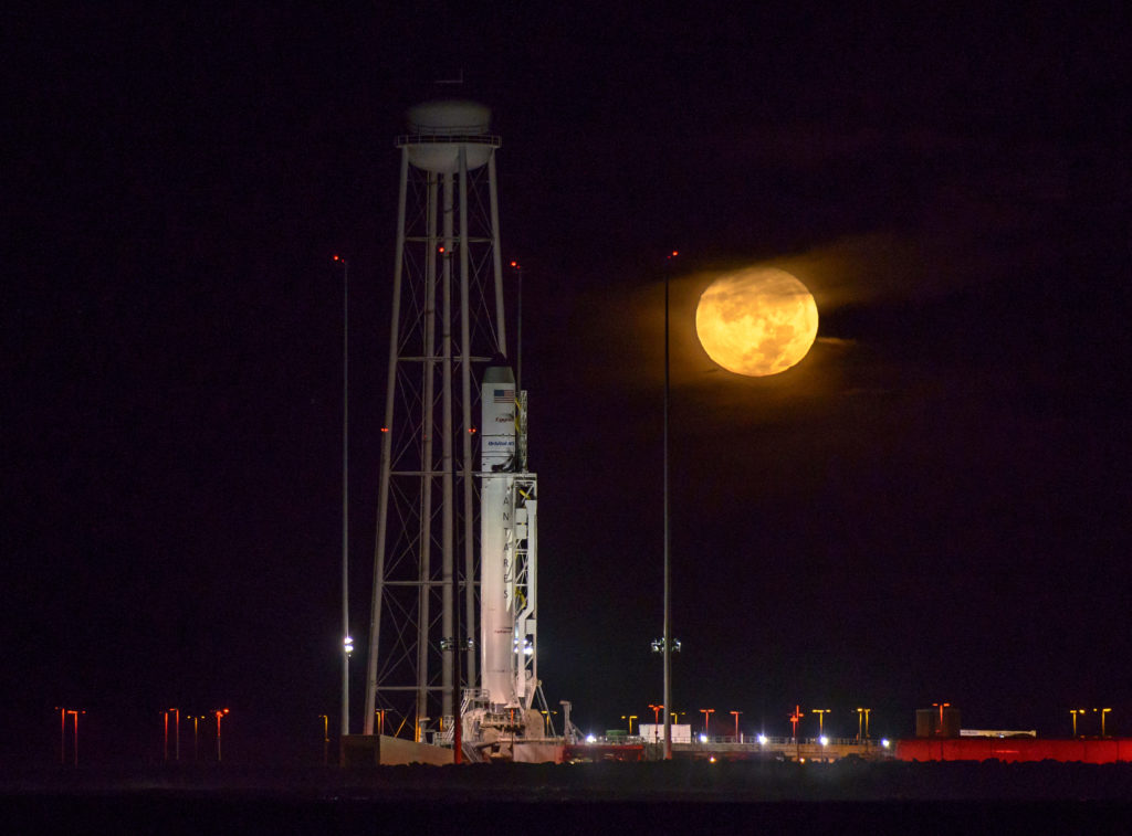 rocket on the pad with orange moon behind