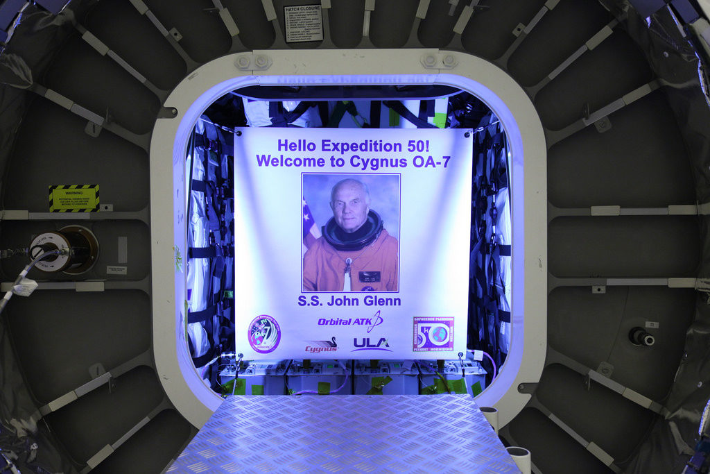 Inside the Payload Hazardous Servicing Facility at NASA's Kennedy Space Center in Florida, the John Glenn banner is attached inside the Orbital ATK Cygnus pressurized cargo module. The Cygnus cargo module has been renamed the S.S. John Glenn to honor the late former Project Mercury and space shuttle astronaut.