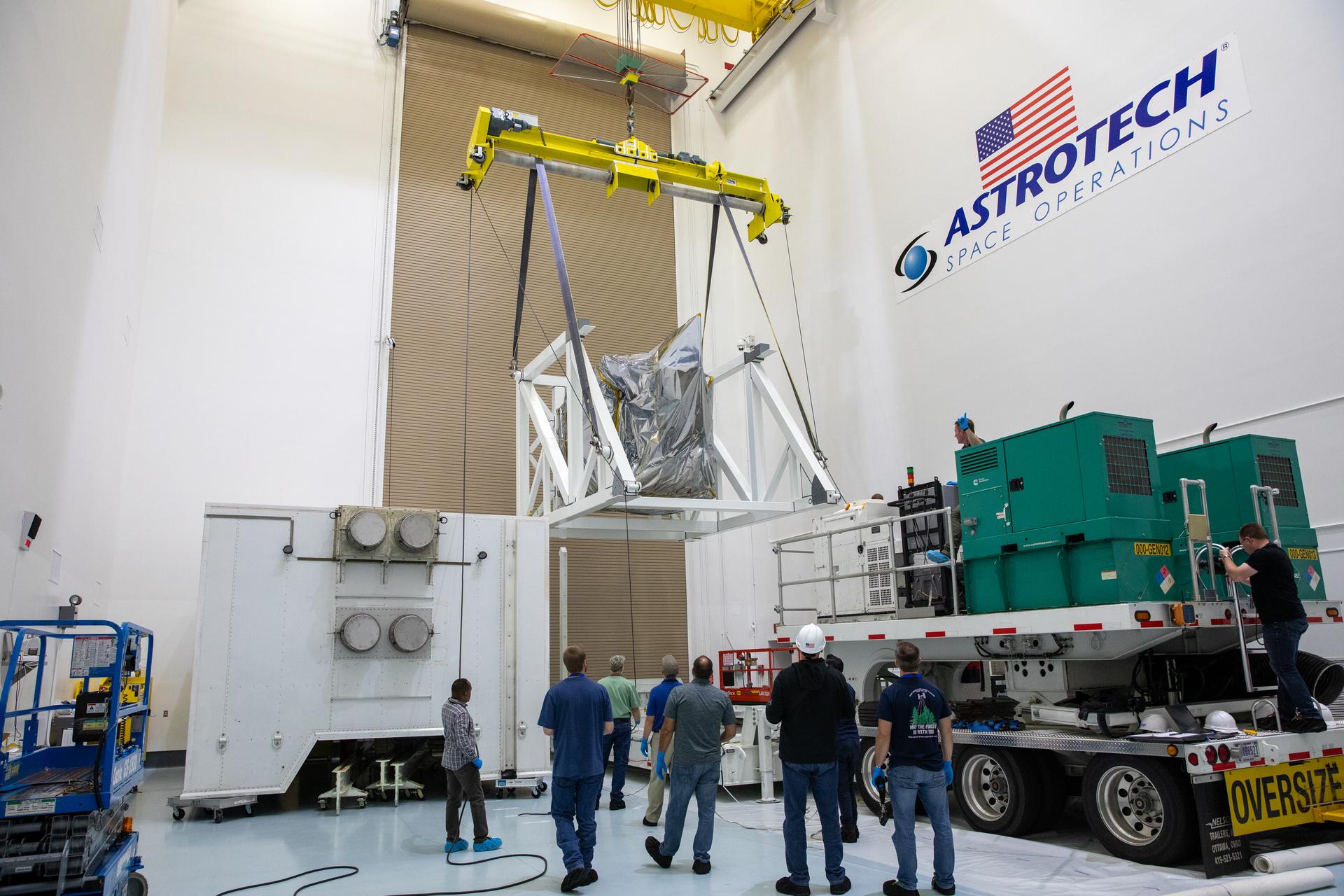 Technicians monitor movement as a crane hoists NASA’s Plankton, Aerosol, Cloud, ocean Ecosystem (PACE) observatory spacecraft after being uncrated on Wednesday, Nov. 15, 2023, at the Astrotech Space Operations Facility near the agency’s Kennedy Space Center in Florida. 