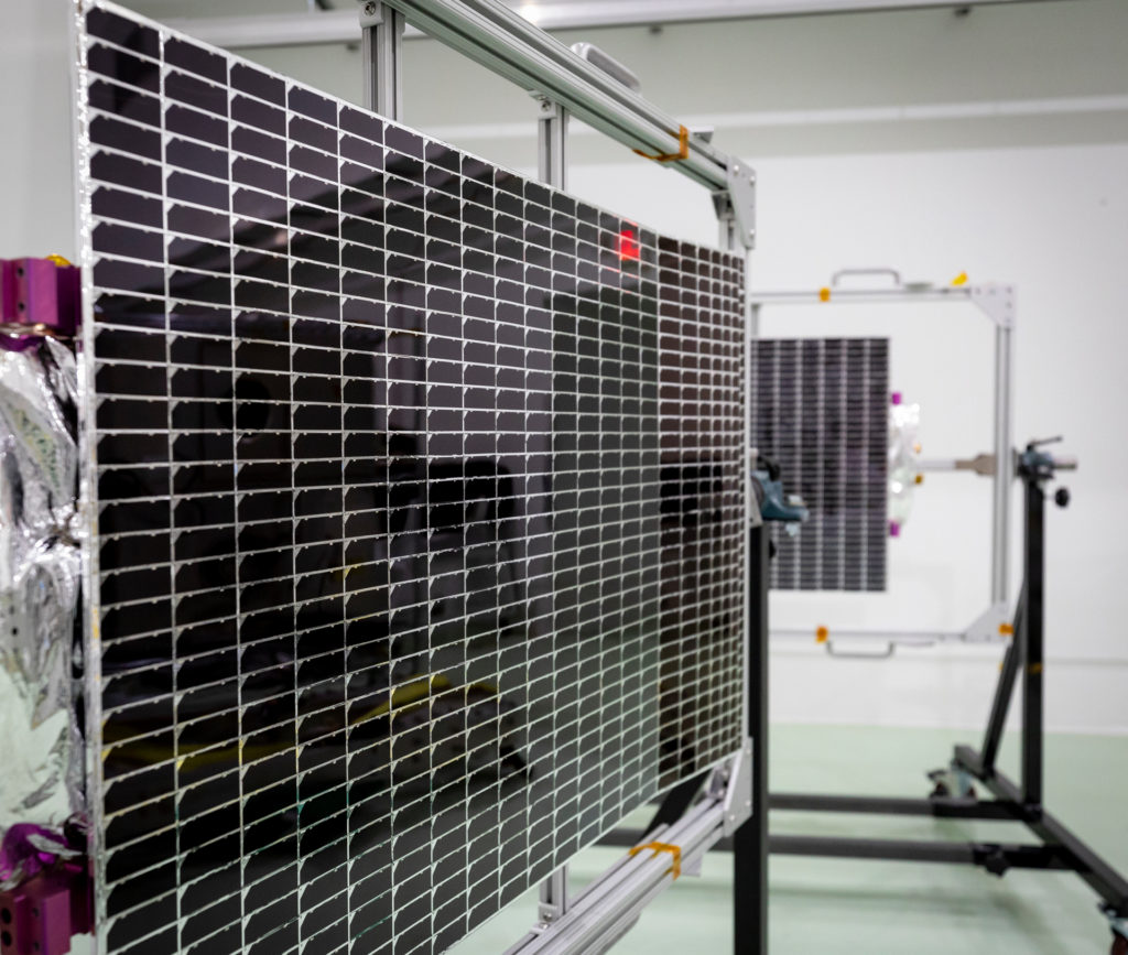 Two solar arrays it on racks in a clean room.