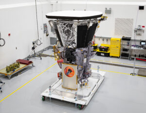 Parker Solar Probe spacecraft in an white room. It's mostly silver and shaped like a cone – smaller on the bottom toward the ground and getting wider toward the top. The top appears white and is flat.