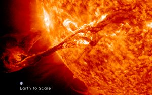 A red Sun shoots off a coronal mass ejection. Below the ejection, Earth is shown to scale. This shows that the coronal mass ejection is many times larger than the Earth.