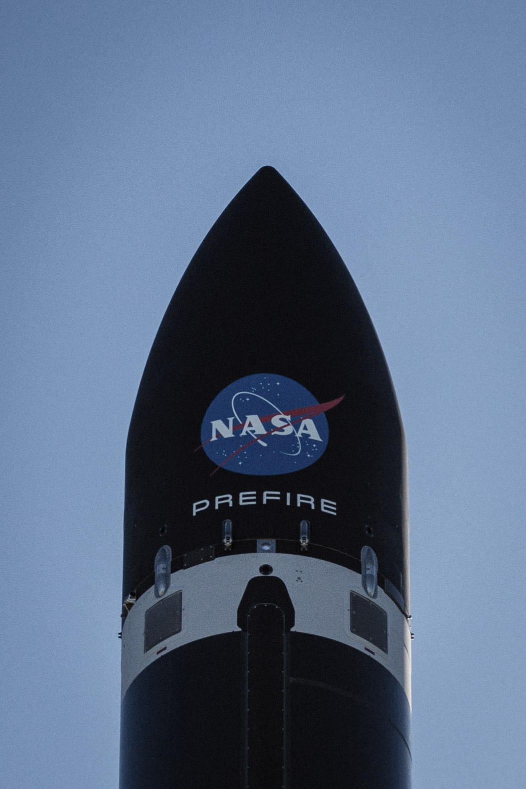 a close up of Rocket Lab's payload fairing while it sits on the launch pad. Painted on it our the NASA logo and the PREFIRE mission name.