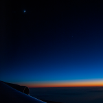 Image through one of SOFIA’s windows, overlooking over one wing with two of the engines in view. The colorful sunset sky and the crescent moon are visible as the team prepares to observe Venus.