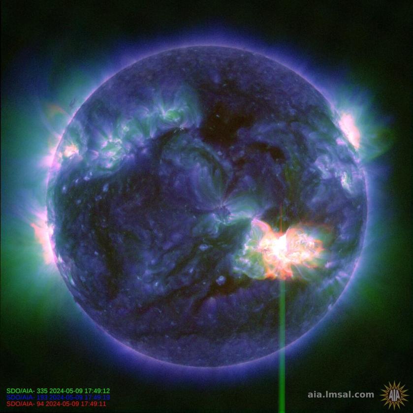 A composite image of the Sun in blue, green, and red shows an X-class flare as a large, bright burst of white and red light in the lower right.