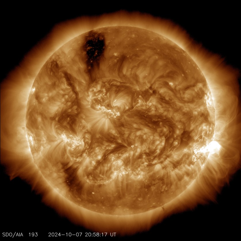 The Sun, shown in shades of gold. It has several dark and bright regions, including a very bright flash of light near the right limb.