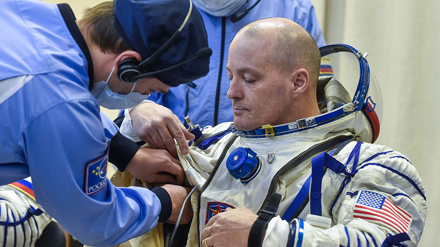 NASA astronaut Scott Tingle is helped into his Russian Sokol spacesuit