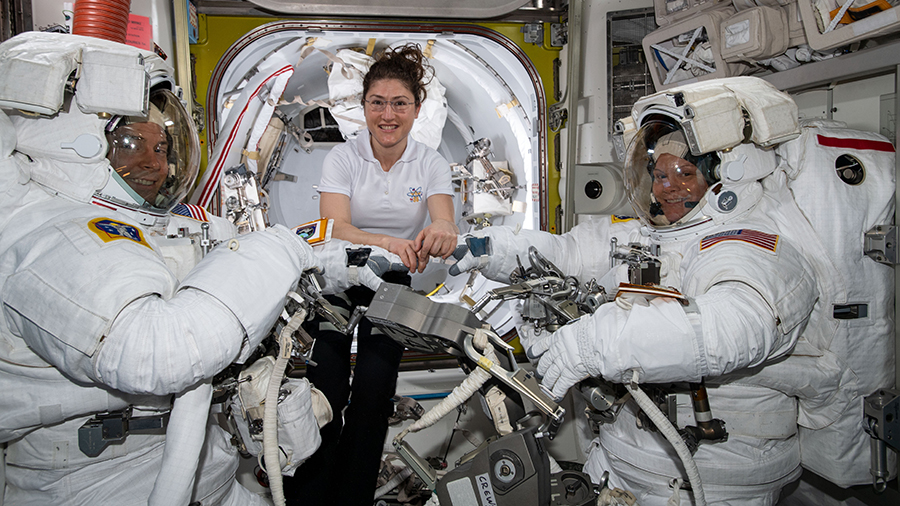 Astronaut Christina Koch assists spacewalkers Nick Hague and Anne McClain