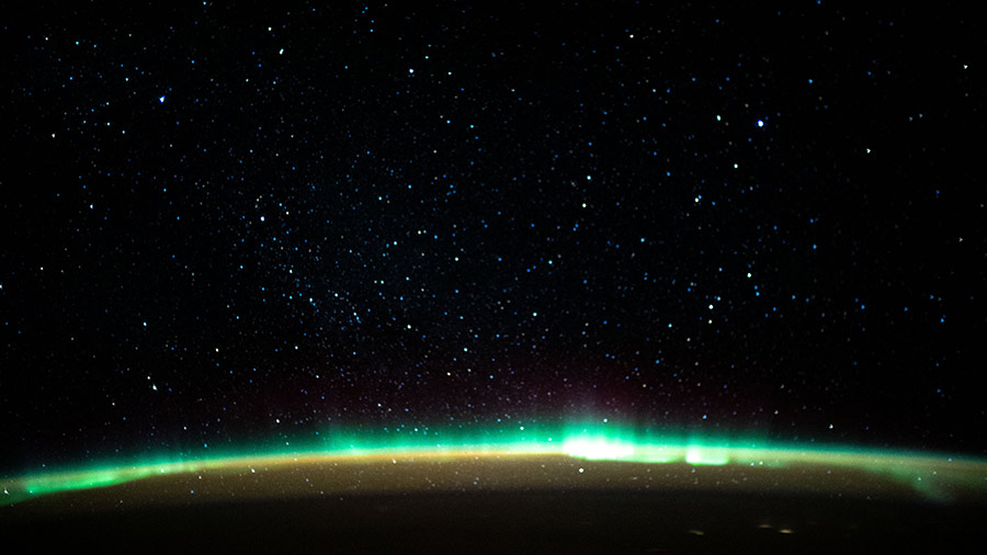 An aurora blankets the Earth beneath a celestial night sky