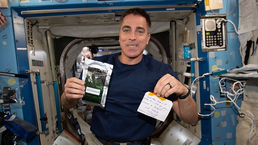 NASA astronaut Chris Cassidy holds a Parmigiana di Melanzane meal packet