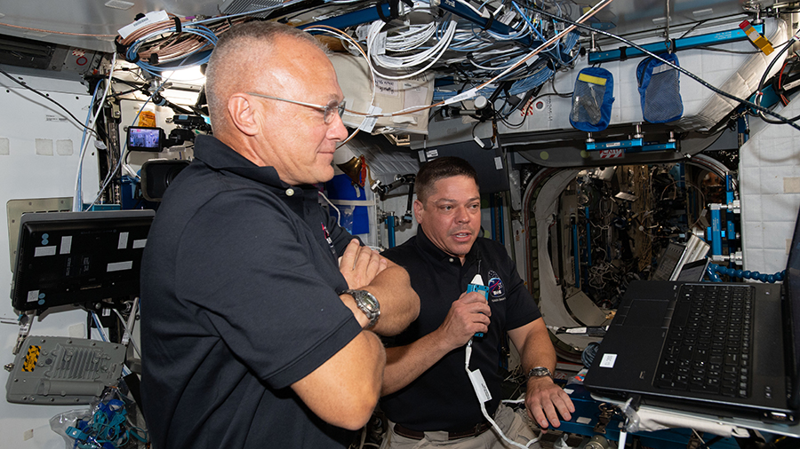 NASA astronauts Doug Hurley (foreground) and Bob Behnken talk to mission controllers on the ground.