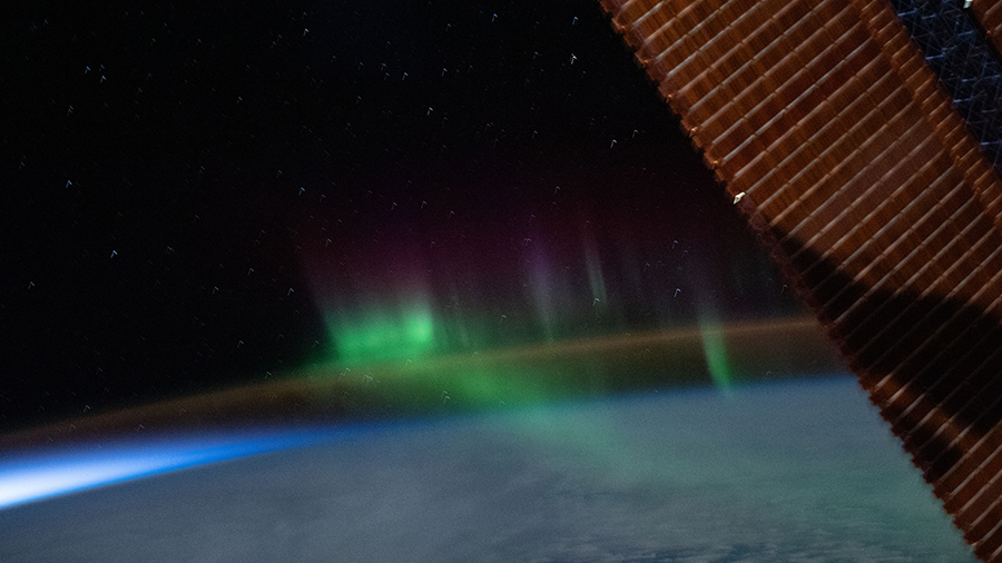 A wispy "aurora australis" seemingly intersects with the Earth's airglow