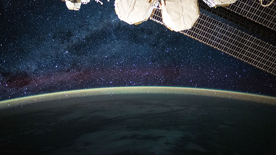 This picture from the station reveals the Milky Way glittering above a bright but exaggerated atmospheric glow that blankets the Earth's horizon.