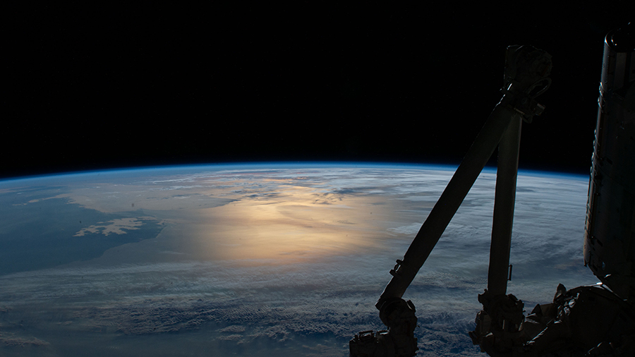 Flying over southern Argentina, this photograph from the space station looks northward with the Sun's glint beaming on the Atlantic Ocean.